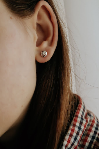 Close up on a light skinned girl's ear with a simple diamond stud earring.